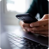 Person using their smart phone and laptop