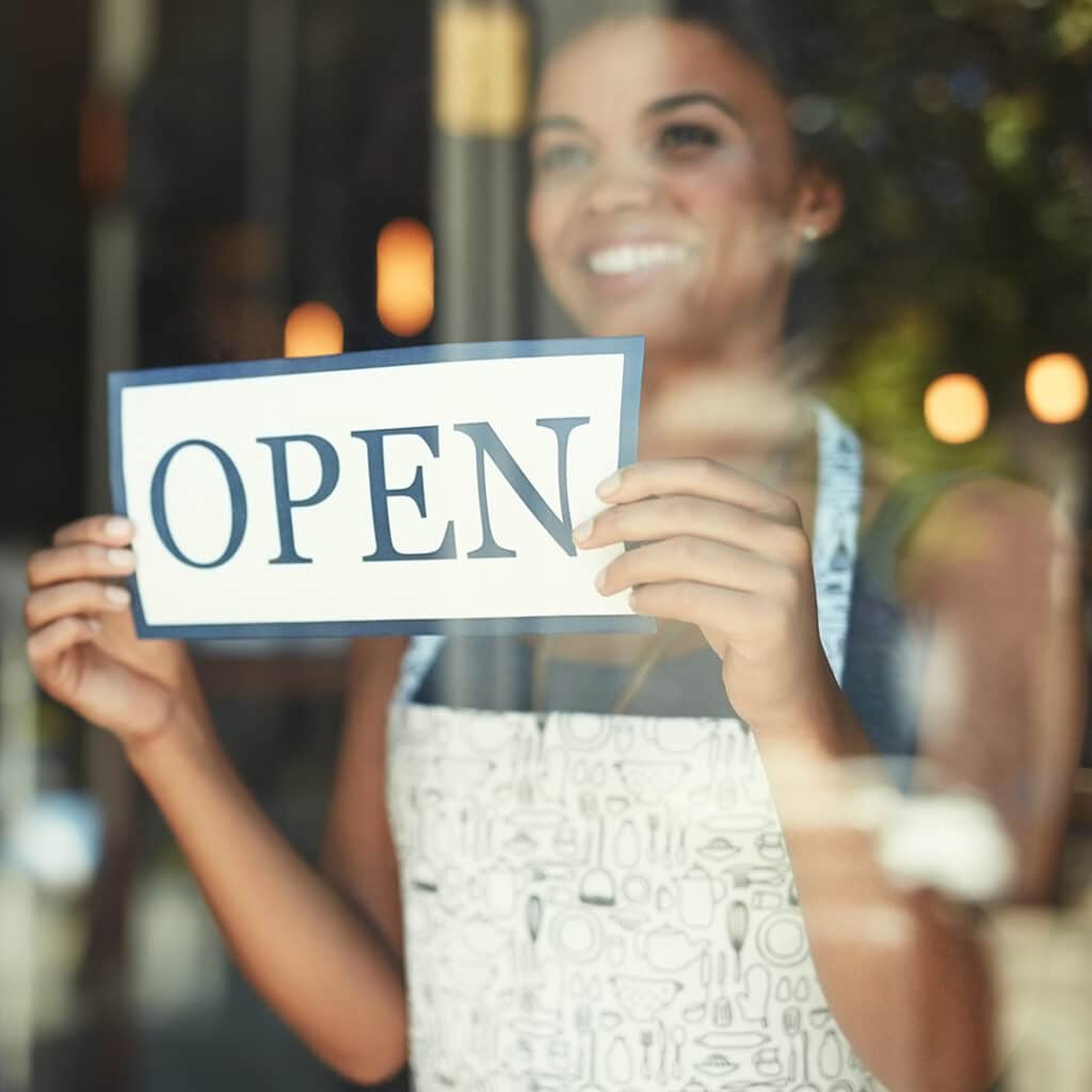 Business women holding an open sign in a store